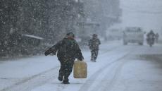 A boy walks on snow as he holds a plastic gallon during snow fall in the Duma neighbourhood of Damascus, December 13, 2013. A powerful winter storm sweeping the eastern Mediterranean this week is causing mayhem across the region and inflicting extra hardships on Syrians convulsed in civil war and on refugees who have fled the fighting.The storm, named Alexa, is expected to last until Saturday, bringing more snow, rain and cold to swathes of Turkey, Syria, Lebanon, Jordan, Israel, the Palestinian territories and Egypt. REUTERS/Bassam Khabieh (SYRIA - Tags: POLITICS CIVIL UNREST) - RTX16H55